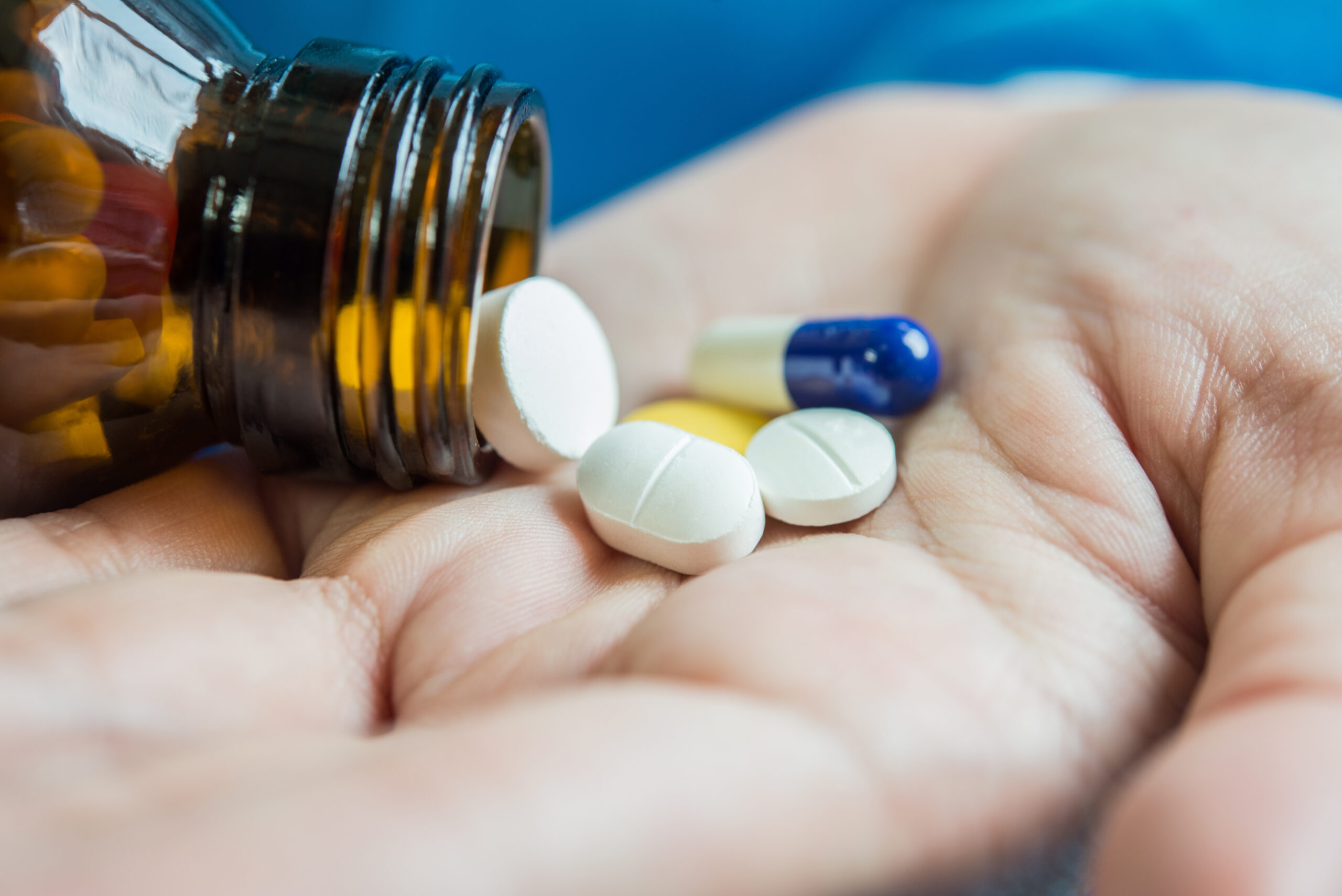 Woman's hand pours the medicine pills out of the bottle