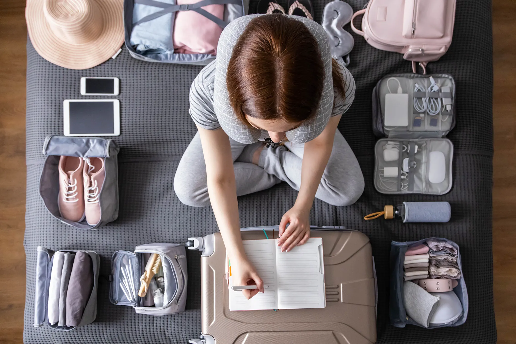 Smiling tourist woman packing suitcase to vacation writing paper list getting ready to travel trip
