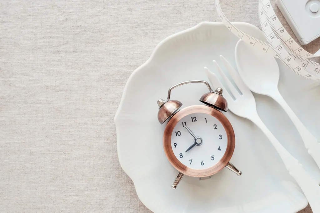  A clock on the plate and tape measure, Intermittent fasting diet concept
