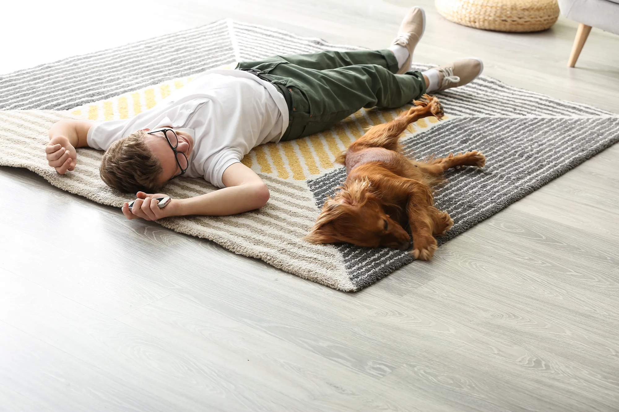 Teenage boy with cute dog lying on carpet at home
