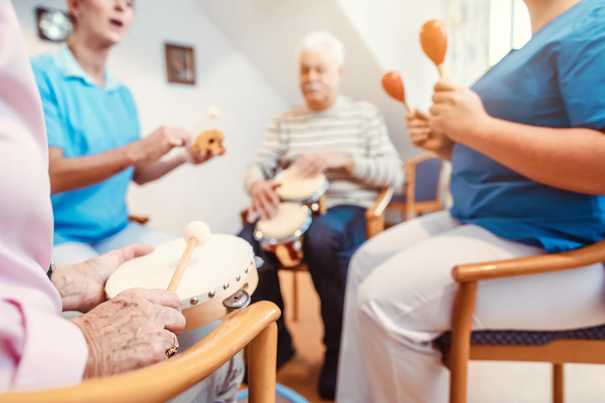 Seniors in nursing home making music with rhythm instruments
