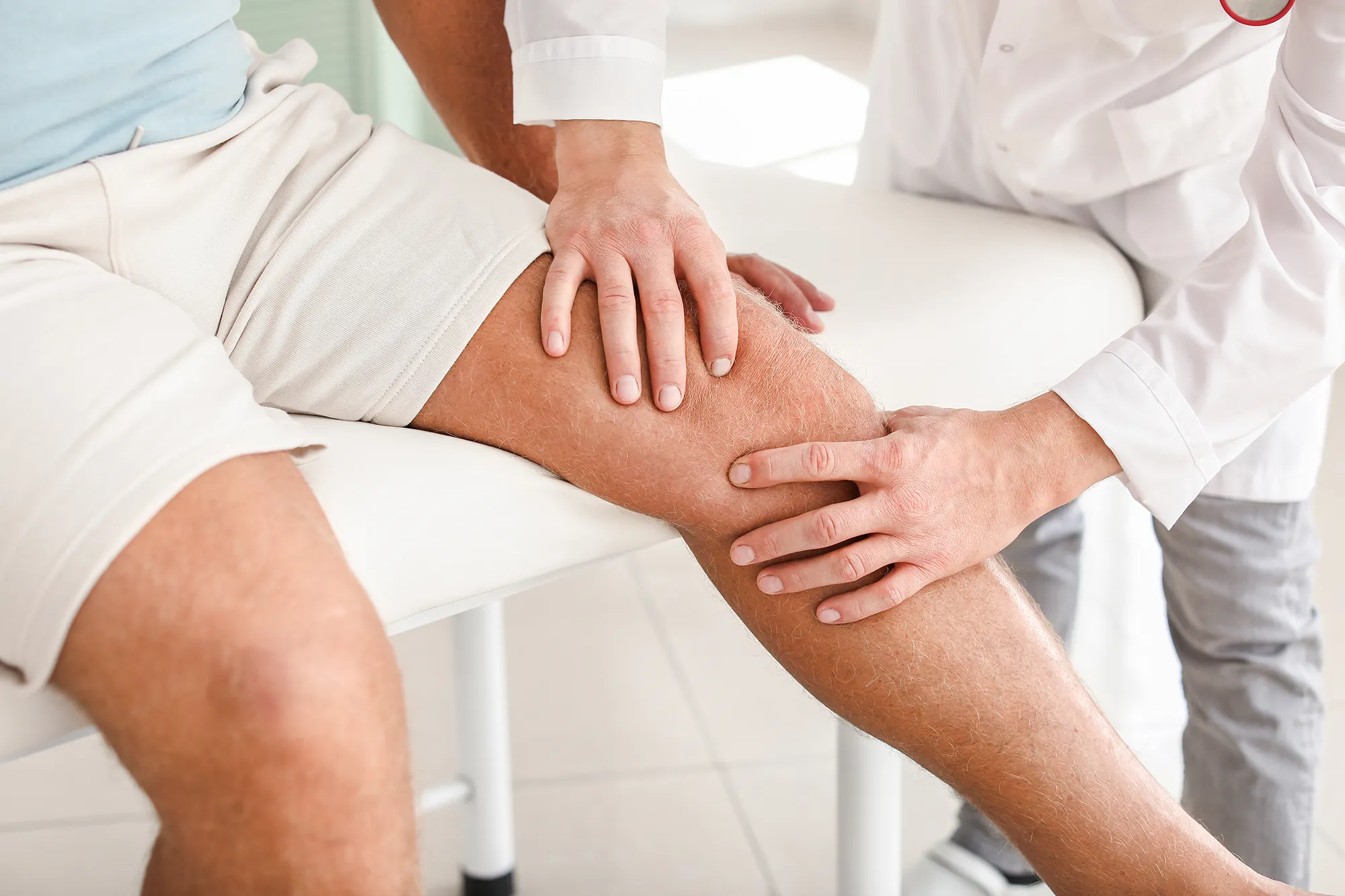 Doctor examining mature man with joint pain in clinic
