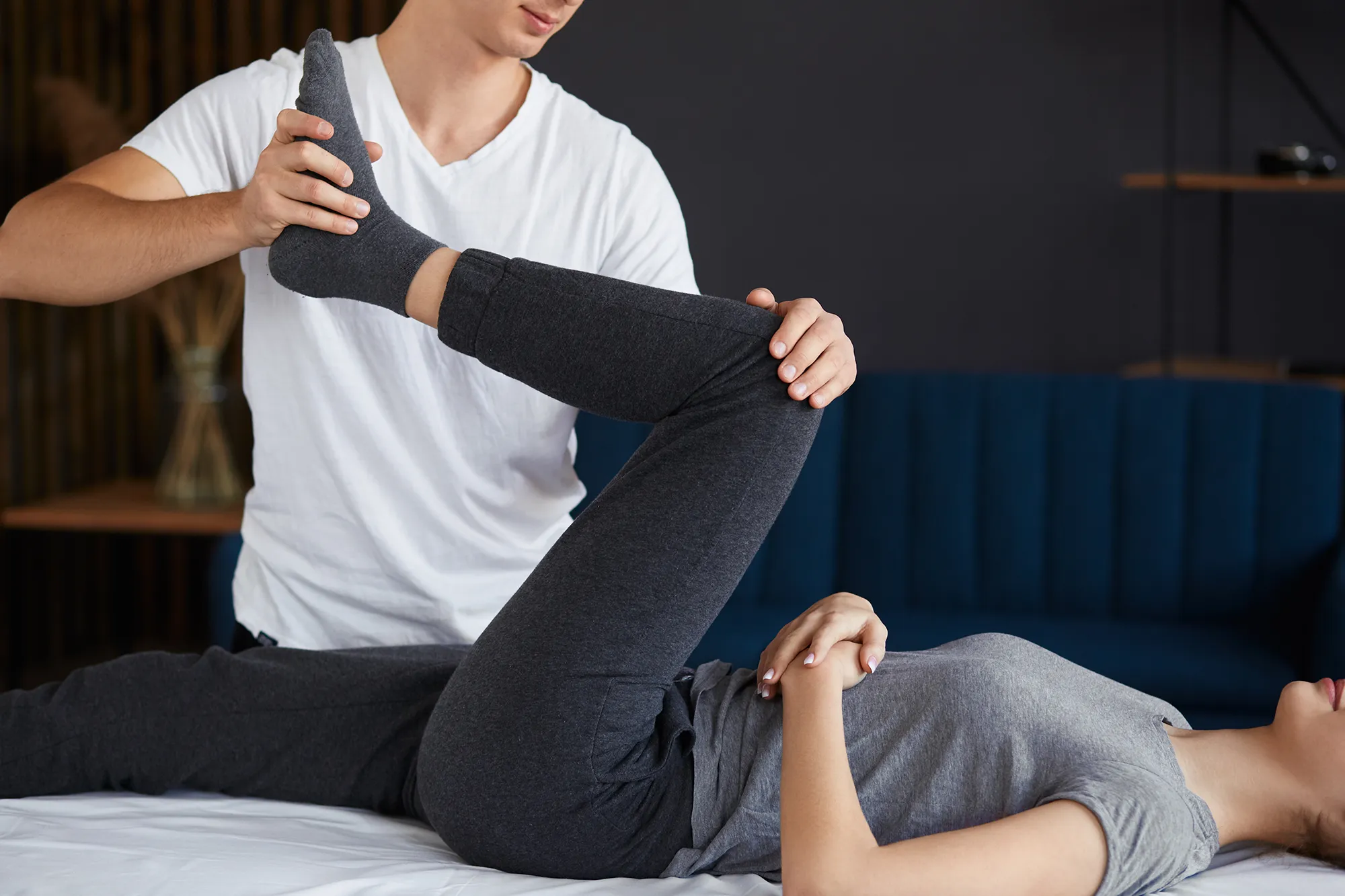 Female patient doing physical exercises with physiotherapist. Male therapist treating injured knee of young athlete.Post traumatic rehabilitation, sport physical therapy, recovery concept. 