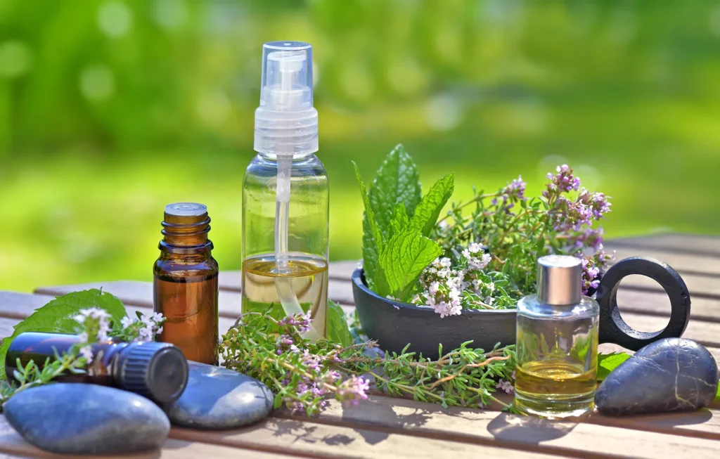 bottles of essential oils on a table with lavender flowers and mint leaf in bowl
