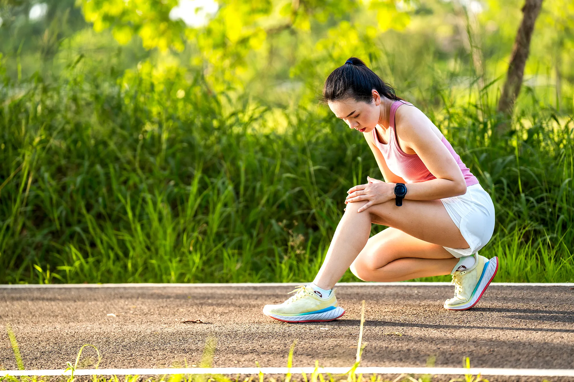 Asian woman accident falling down on floor in the park while running exercise with knee pain