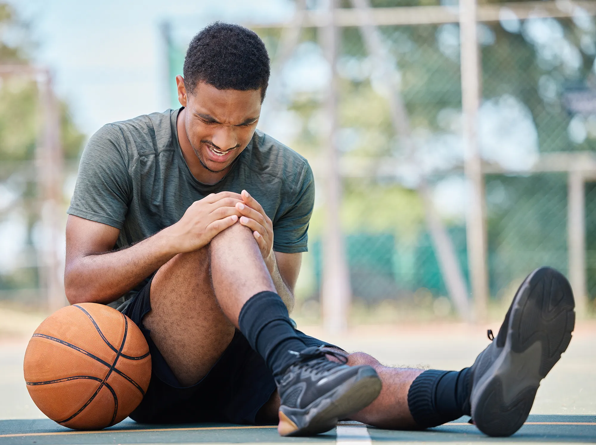 Basketball court, man and injury, knee pain and joint pain, fitness emergency and first aid accident, risk and bone health. Black man, basketball player and leg pain, muscle inflammation and problem
