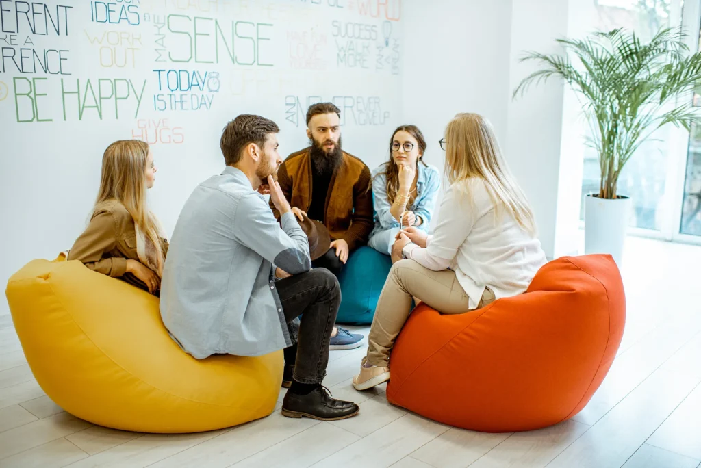 Group of diverse people sitting in a circle during the psychological therapy in the modern office. Feeling support from each other
